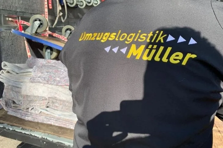 umzugshelfer mit firmenlogo laedt schutzdecken aus umzugswagen